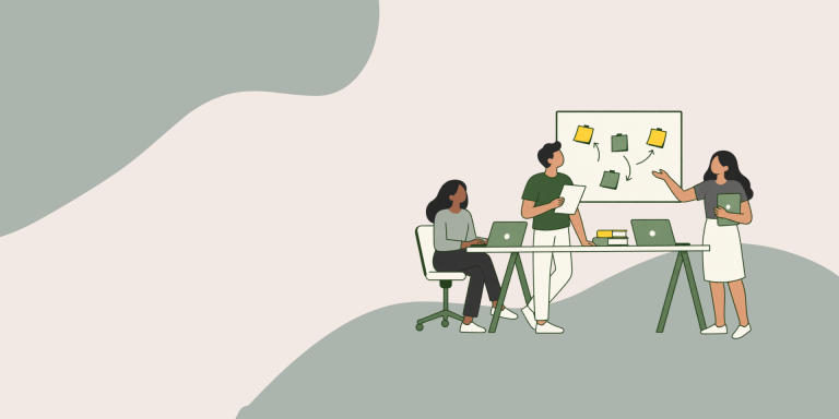 Two women and one man standing and sitting at a table looking at a board with sticky notes on.